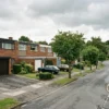 New Town housing estate street in Warrington with terraced homes, integral garages and footpaths separating houses from the road